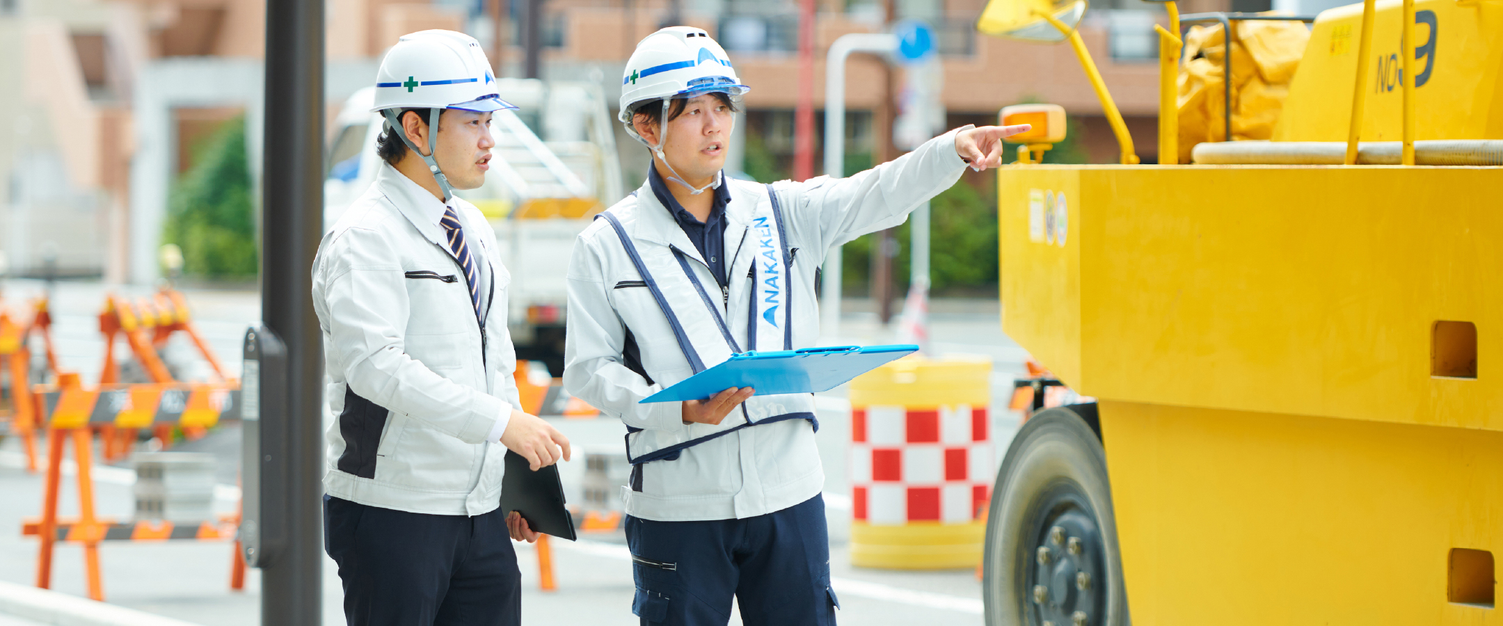 作業服の男性二人が工事現場で進行確認している様子