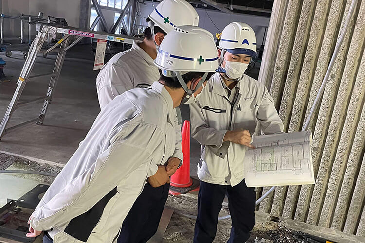 工事現場で資料を見ながら勉強する先輩社員と新人社員