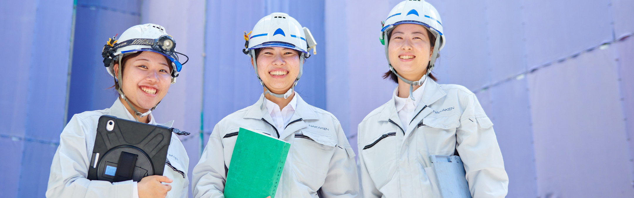 ヘルメットに作業服の女性三人が笑顔で並んでいる写真