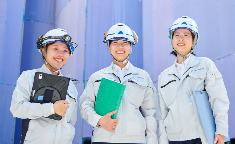 作業着姿の女性3人が笑っている写真